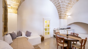 A cozy room with a bed, a dining table with chairs, a kitchen area, and a white door with glass panels. - Apartment in 'Dimora S' Hotel with Private Terrace, Wi-Fi, and Air Conditioning (Sogliano Cavour)