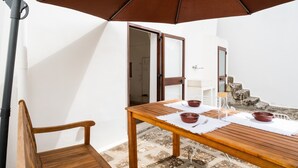 A wooden table with a white tablecloth, two red bowls, and a glass pitcher on a balcony with a brown umbrella. - Apartment in 'Dimora S' Hotel with Private Terrace, Wi-Fi, and Air Conditioning (Sogliano Cavour)