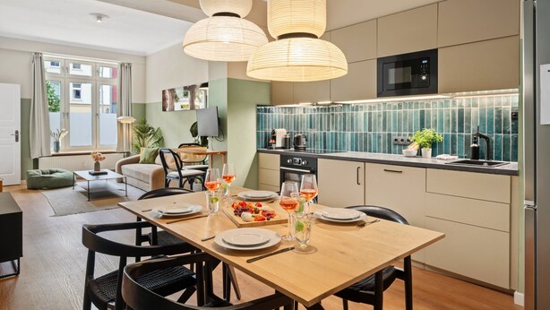 A modern kitchen with a dining area, wooden table, chairs, and pendant lights. - Super central, 2 bedrooms (Berlin)