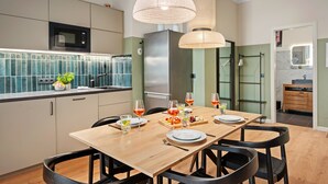 A modern kitchen with a dining area, featuring a wooden table, black chairs, and a stainless steel refrigerator. - Super central, 2 bedrooms (Berlin)