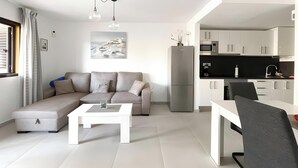 Uma sala de estar moderna com sofá, mesa de centro, mesa de jantar e área de cozinha com armários e eletrodomésticos.