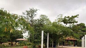 A swimming pool with metal ladders, surrounded by greenery and a gazebo.