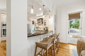 A modern kitchen with white cabinetry, stainless steel appliances, a central island with bar stools, and pendant lighting. - Watersound Home w/ LSV and Community Pool (Watersound)