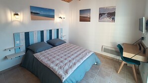 Une chambre à coucher avec un lit, un bureau et des œuvres d’art accrochées au mur.