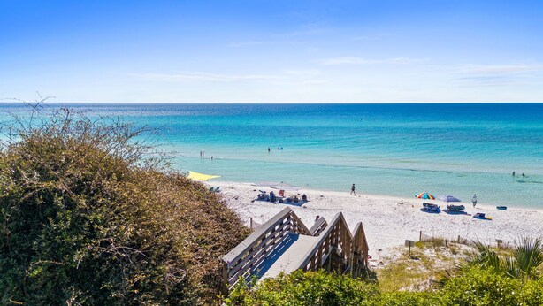 A beach with clear blue water, a wooden boardwalk, and beach umbrellas. - Retreat Close to Beachw/ Pool and Screened Porch (Santa Rosa Beach)