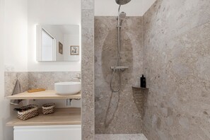 Ein modernes Badezimmer mit Dusche, Waschbecken und Spiegel.