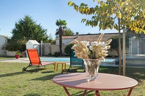 A patio with a round table, a chair, and a vase with flowers. - Bed and Breakfast 'Suite Les Cabanes' with Shared Pool, Shared Garden and Wi-Fi (La Brée-les-Bains)