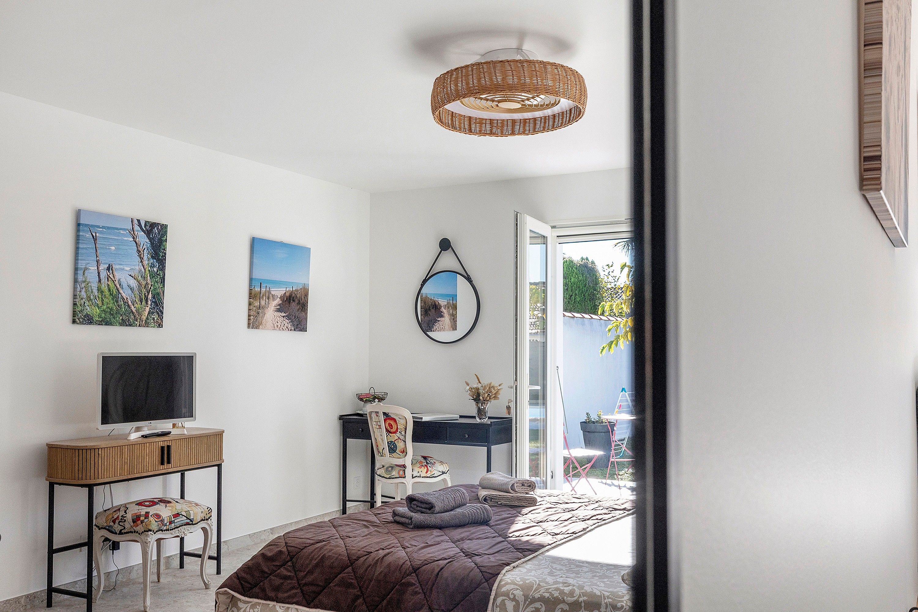 Une chambre à coucher comprenant un lit, un bureau, une chaise, un téléviseur et des œuvres d’art accrochées au mur.