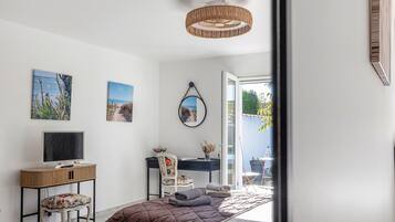 Une chambre à coucher comprenant un lit, un bureau, une chaise, un téléviseur et des œuvres d’art accrochées au mur.