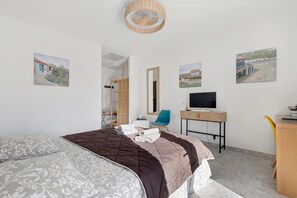 A bedroom with a bed, a desk, a chair, a television, and artwork on the walls. - Bed and Breakfast 'Suite Les Cabanes' with Shared Pool, Shared Garden and Wi-Fi (La Brée-les-Bains)