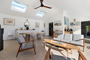 A spacious living area with a ceiling fan, a dining table with chairs, a sofa, and artwork on the walls. - Bed and Breakfast 'Suite Les Cabanes' with Shared Pool, Shared Garden and Wi-Fi (La Brée-les-Bains)
