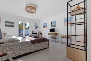 Une chambre à coucher avec un lit, un bureau, une chaise, une télévision et une étagère avec des vêtements.