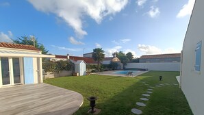 Un jardin avec une piscine, une terrasse en bois et un petit abri de jardin.
