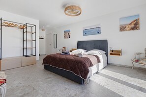 A bedroom with a bed, a wardrobe, a hanging light fixture, and wall art. - Bed and Breakfast 'Suite Les Plages' with Shared Pool, Shared Garden and Wi-Fi (La Brée-les-Bains)