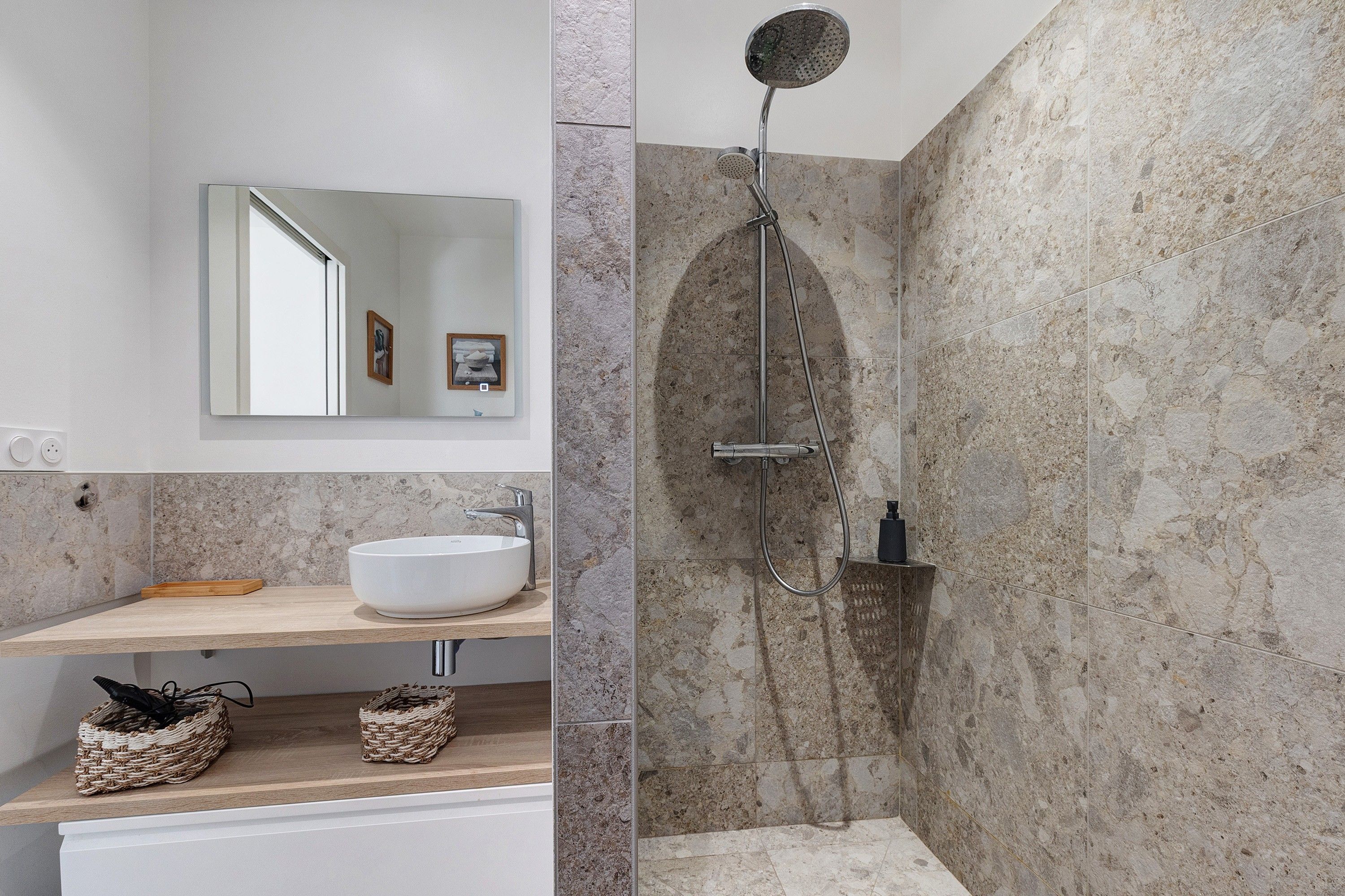 Een moderne badkamer met een vrijstaand badkamermeubel, een spiegel en een douche met een gebogen douchekop.