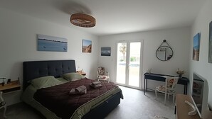 Une chambre à coucher comprenant un lit, un bureau, une chaise, un miroir et des œuvres d’art accrochées aux murs.