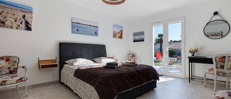 Un dormitorio con cama, una silla, un escritorio y ventana.