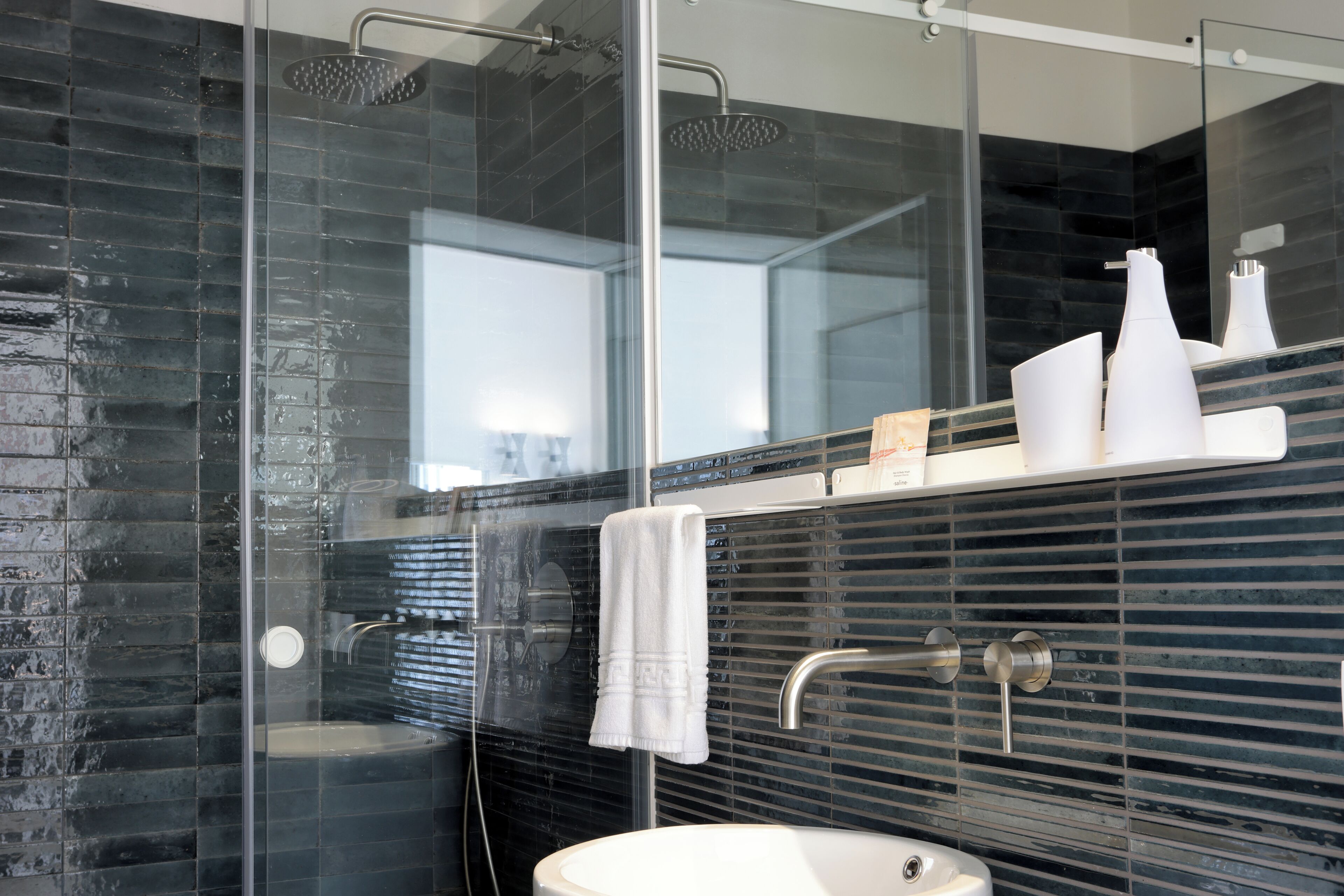 A modern bathroom with a glass-enclosed shower, a white sink, and a mirror above the sink.