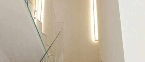 A staircase with glass railings and a light fixture on the wall.