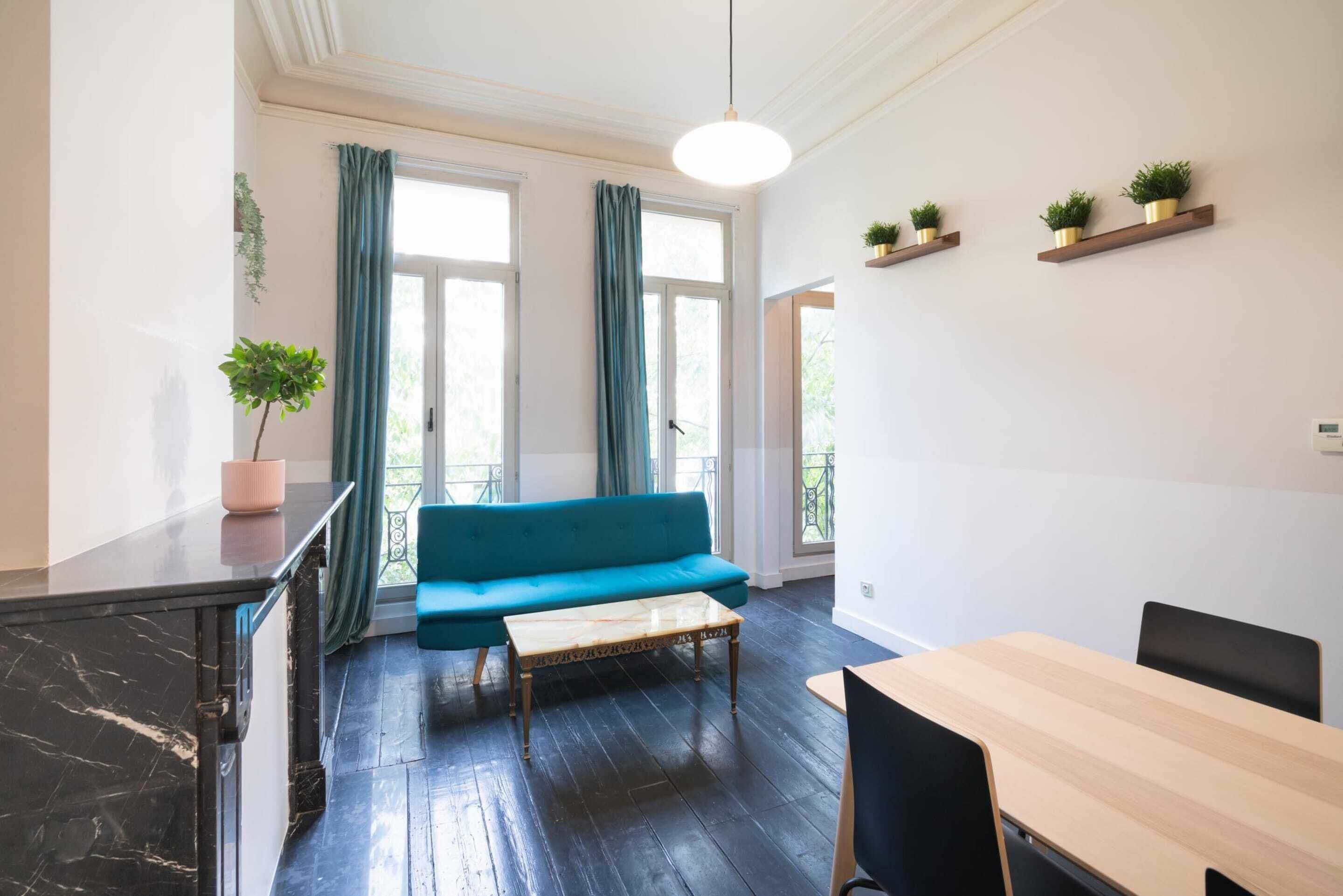 Quarto moderno com sofá azul, mesa de madeira e armário preto.