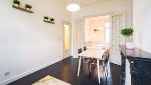 Un interior moderno con zona de comedor, suelo de madera oscura y estanterías empotradas con plantas.