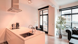 A modern kitchen with a built-in island, a coffee maker, and a potted plant. - Spacious Apartment in Heart of Antwerp (Antwerp)