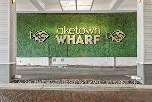 Ein Gebäudeeingang mit einer grünen Wand und der Aufschrift 'laketown WHARF' zusammen mit dekorativen Fischsymbolen.