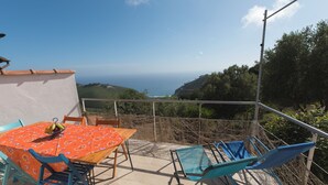A terrace with a table and chairs, a railing, and a view of the ocean. - Grandparents' Shelter between Sky and Sea (Lazio)