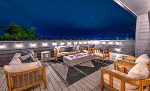 An outdoor seating area with wicker furniture, a fire pit, and string lights. - LUX 4BR/4BA Home w/ Game Rm & Hot Tub | Sleeps 12+ (Nashville)