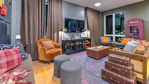 Una sala de estar moderna con un sofá, un sillón, un reposapiés y un aparador con objetos decorativos.