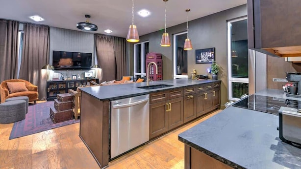 Una cocina moderna con una isla central, electrodomésticos de acero inoxidable e iluminación colgante.