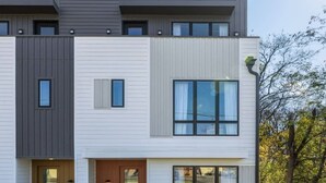 Una casa moderna de dos pisos con entrada frontal, ventanas amplias y césped cuidado.