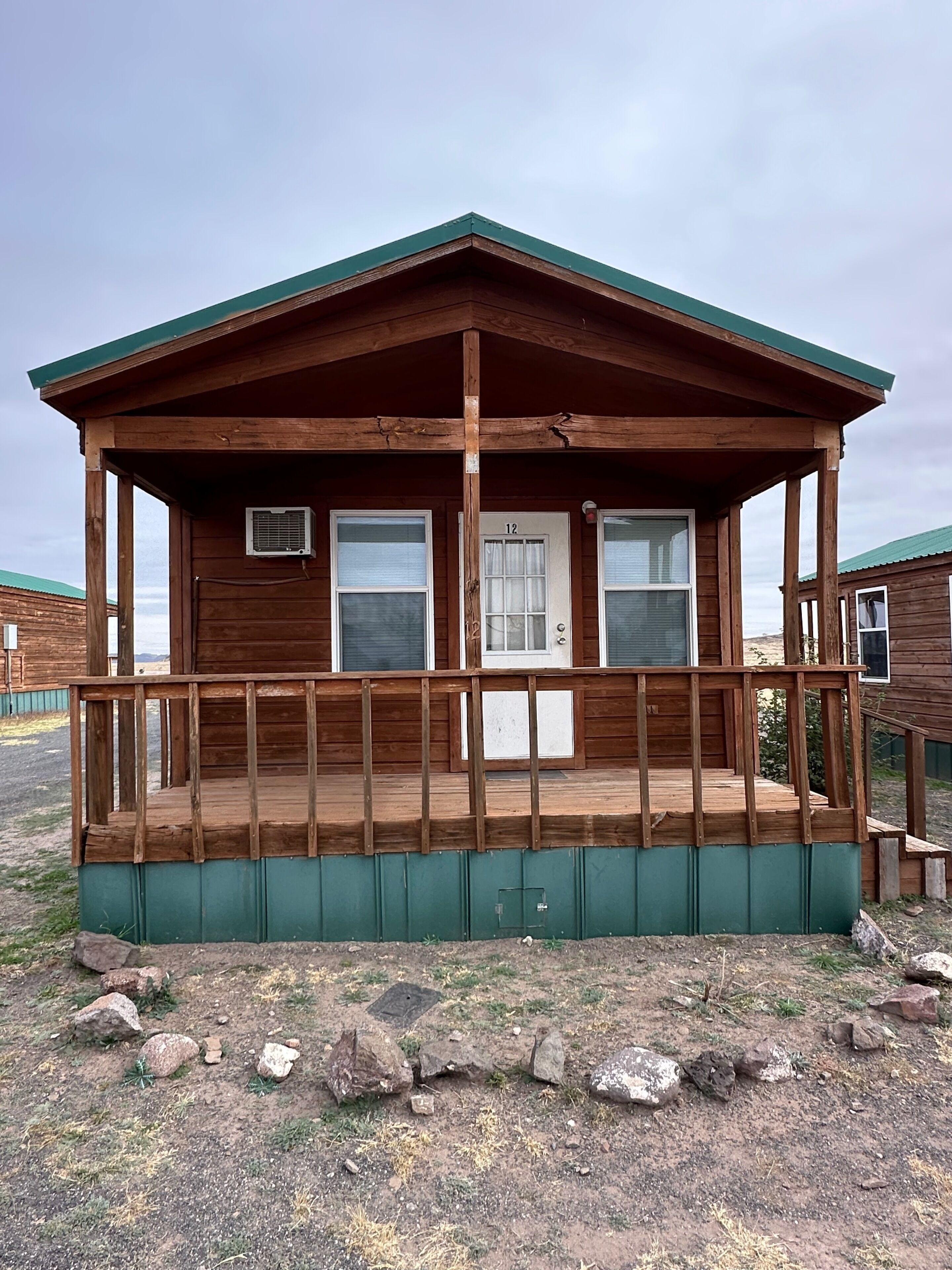 A wooden cabin with a porch, a door labeled '12', and a small window.