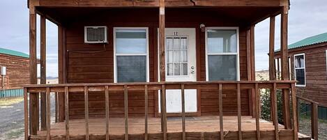 A wooden cabin with a porch, a door labeled '12', and a small window.