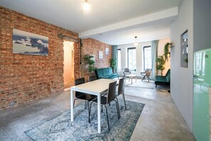 A dining area with a brick wall, a table with chairs, and a green sofa. - The Industrial Apartments 2bbknon Smkwi-fi (Antwerp)