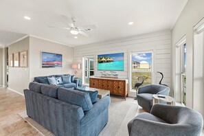 Ein Wohnzimmer mit Sofa, Sesseln, Fernseher und Blick auf den Ozean.