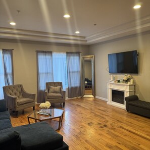 Ein Wohnzimmer mit Kamin, Flachbildfernseher und zwei Sesseln.