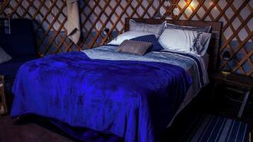Una cama con manta azul, cabecero de madera y varios almohadones.