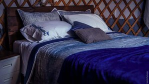 A bed with a wooden headboard, multiple pillows, and a blue blanket.