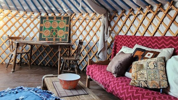 An interior with a wooden table, a patterned rug, a sofa with cushions, and a lattice wall.