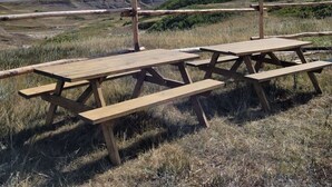 A picnic table set in a natural landscape with a clear sky.