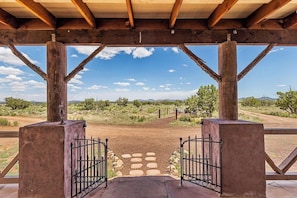 Un espacio al aire libre techado con vista a un sendero de tierra y vegetación escasa.