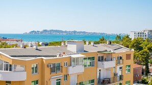 Ein mehrstöckiges Gebäude mit Balkonen, einer flachen Dachterrasse und Blick aufs Meer.