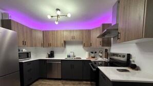 Een moderne keuken met houten kastjes, een roestvrijstalen koelkast, een magnetron, een vaatwasser, een koffiezetapparaat en een fornuis.