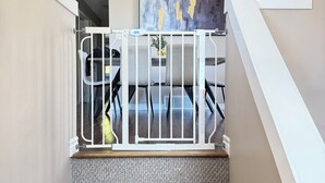 Een trap met een witte leuning, een grijs vloerkleed en een hanglamp.