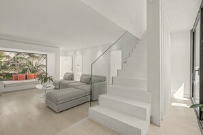 Ein modernes Wohnzimmer mit einem grauen Ecksofa, einem weißen Couchtisch und einer Treppe mit Glastrennläufen.