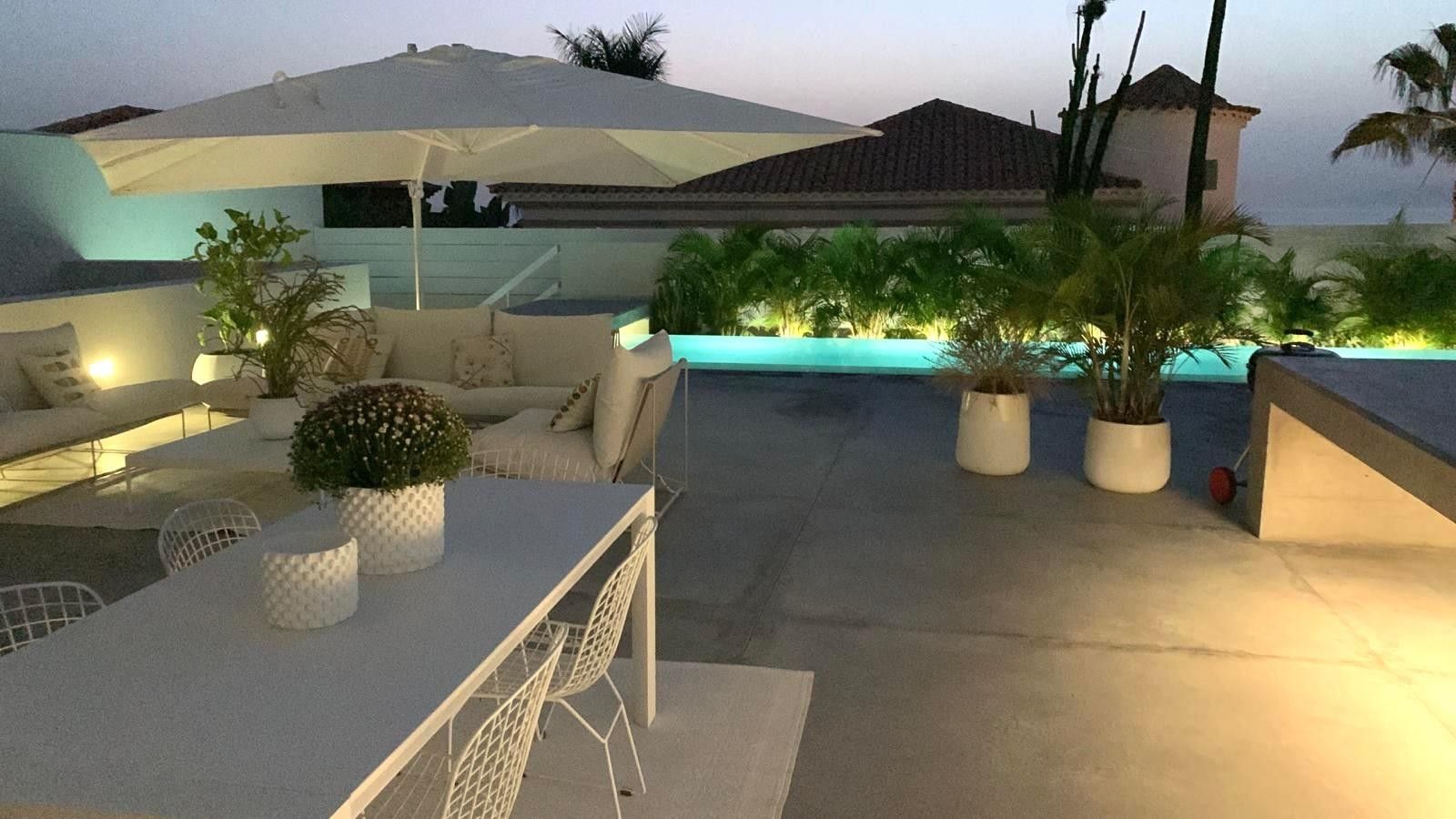 Un patio al aire libre con piscina, mobiliario y plantas en macetas.