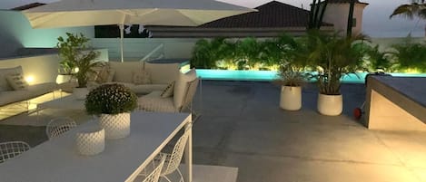 Un patio al aire libre con piscina, mobiliario y plantas en macetas.