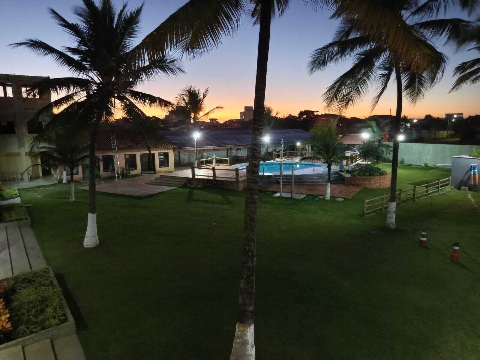 Zona residencial con piscina, palmeras y un edificio de techo con tejas.