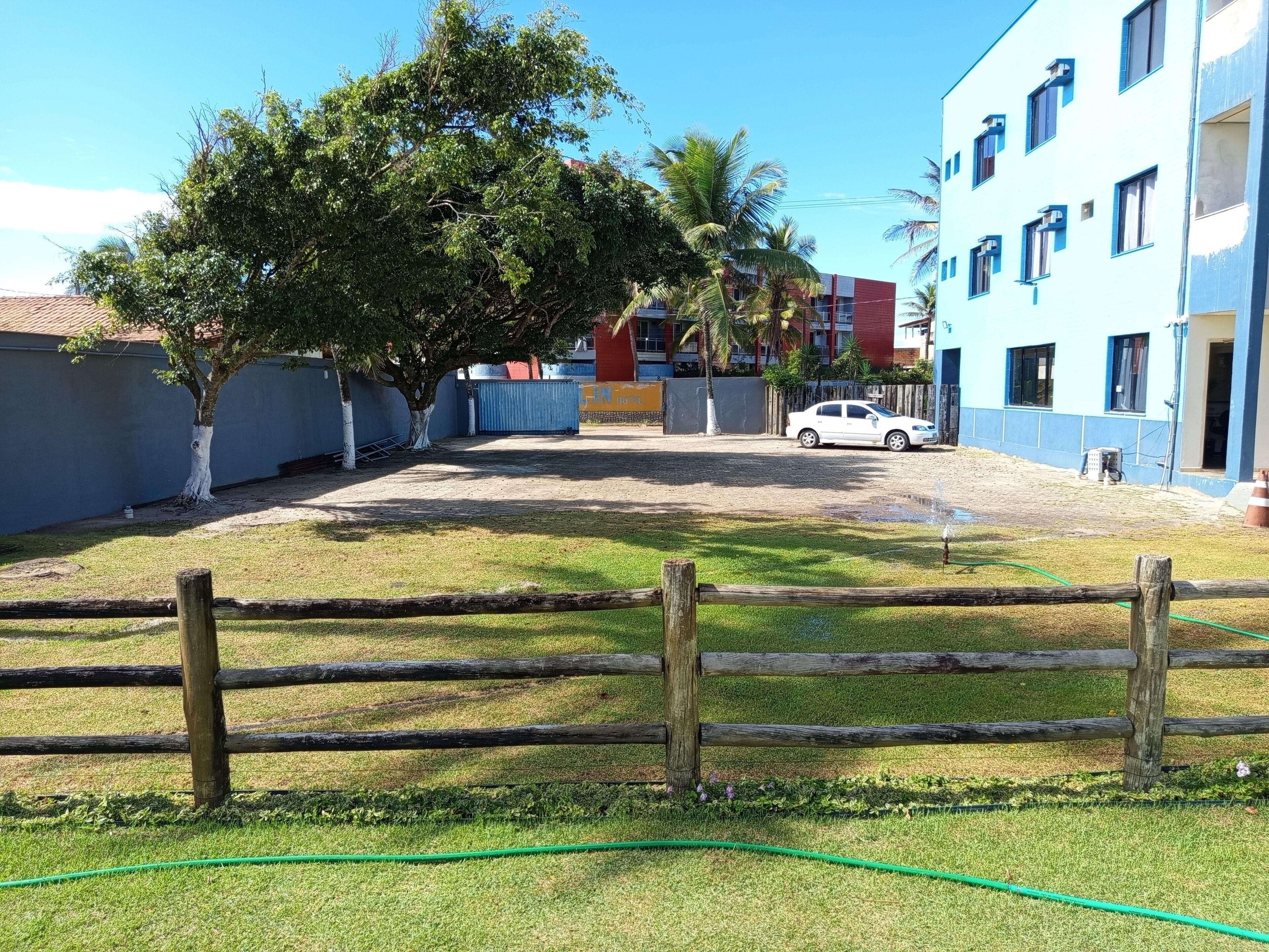 A courtyard with a tree, a white car, and a building with blue and red exterior walls.